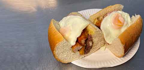 Example of a breakfast roll with two eggs, sausages, bacon, hashbrown and black pudding